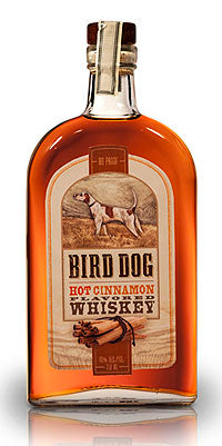 Bottle of Bird Dog Hot Cinnamon Whiskey with a label featuring a dog and cinnamon stick.