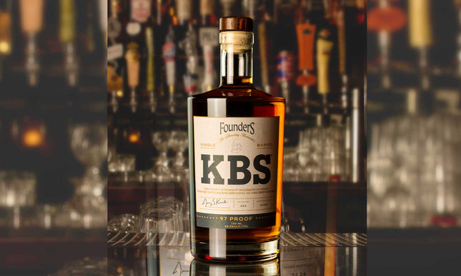 Bottle of Founders KBS whiskey on a bar with blurred bottles and glasses in the background